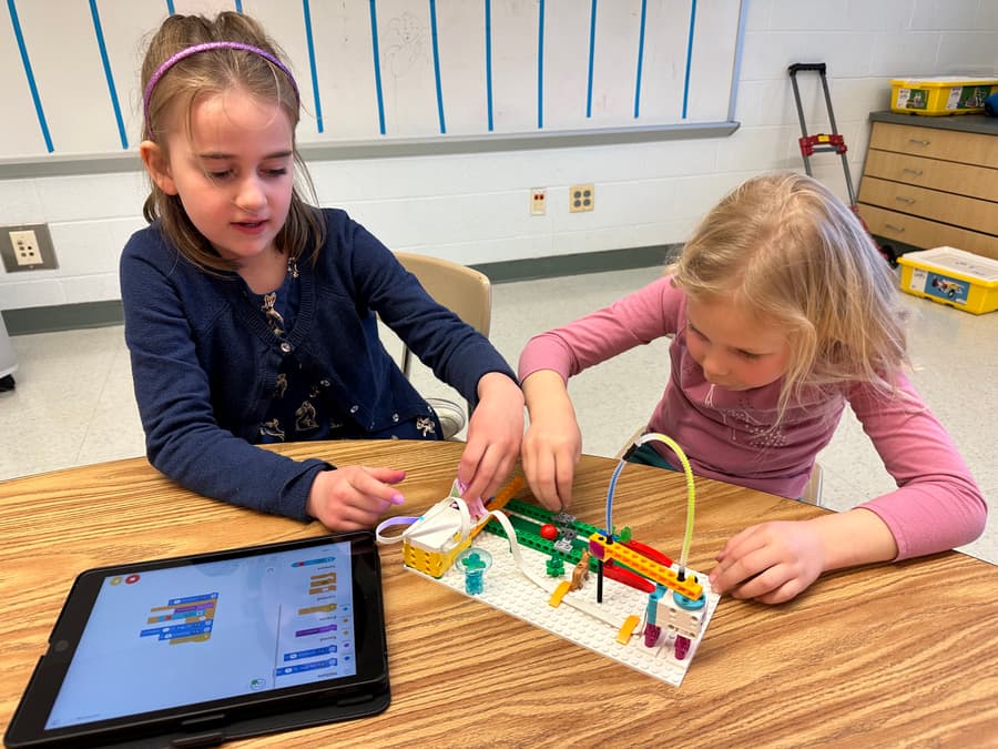 Two students building a robotics project at a desk