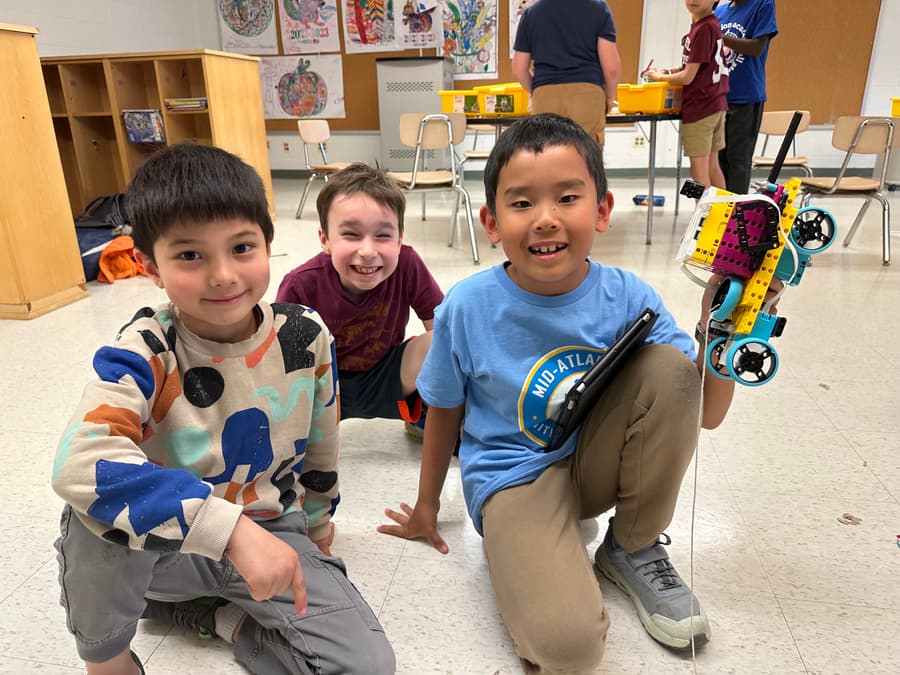 Campers smiling on the floor with the robot they built